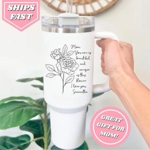 May include: White stainless steel travel mug with a black floral design and the text "Mom, You are as beautiful and unique as this flower. I love you, Samantha".
