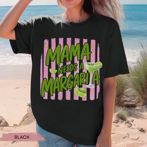 May include: Black t-shirt with the text "MAMA NEEDS A MARGARITA" in green, with a margarita glass and lime slices. The text is set against a pink and white striped background.