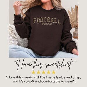May include: A dark brown sweatshirt with the text "FOOTBALL mama" in a leopard print design. The sweatshirt is a crew neck style and is made of a soft material. The image also includes the text "I love this sweatshirt".