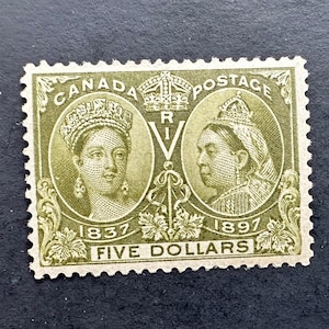 May include: A vintage Canadian postage stamp featuring two oval portraits of a crowned woman, with the text "CANADA POSTAGE" and "FIVE DOLLARS". The stamp is olive green with the years 1837 and 1897.
