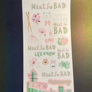 Puede incluir: Una hoja de pegatinas con varios diseños y texto en verde y rosa. Las pegatinas incluyen elementos florales, animales de dibujos animados y frases como "Want So BAD" y "Love is so intuitive."
