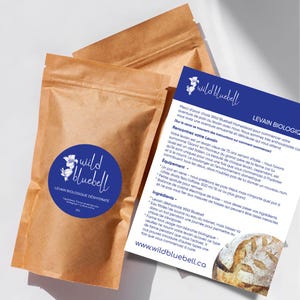 May include: A brown paper bag with a white sticker that says "Wild Bluebell" and "Levain Biologique Deshydrate" in blue text. The bag is next to a white card with blue text that says "Wild Bluebell" and "Levain Biologique". The card has instructions on how to use the levain.