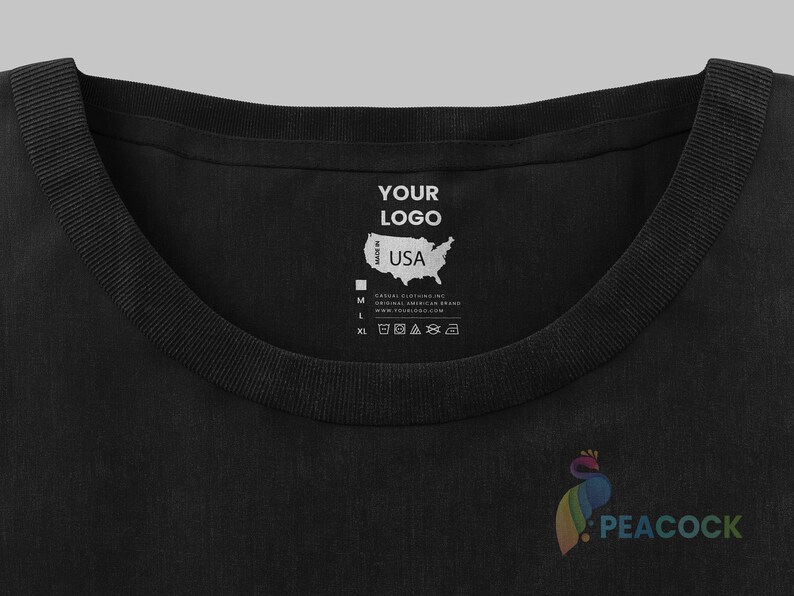 May include: Black t-shirt with a white label that says "YOUR LOGO" and "Made in USA". The label also includes a map of the United States and size information. The t-shirt has a peacock logo on the bottom right.