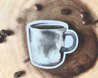 May include: A watercolor-style sticker of a coffee mug filled with dark liquid. The mug is gray with a white outline and a curved handle. Several coffee beans are scattered around the mug on a wooden surface, suggesting a coffee theme.