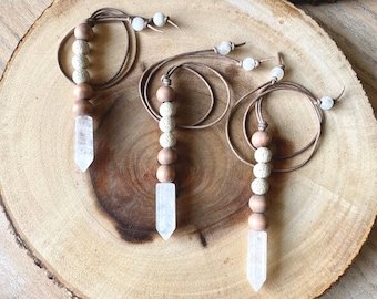 May include: Three crystal point necklaces with brown and white beads. Each necklace has a different length and features a crystal point pendant.