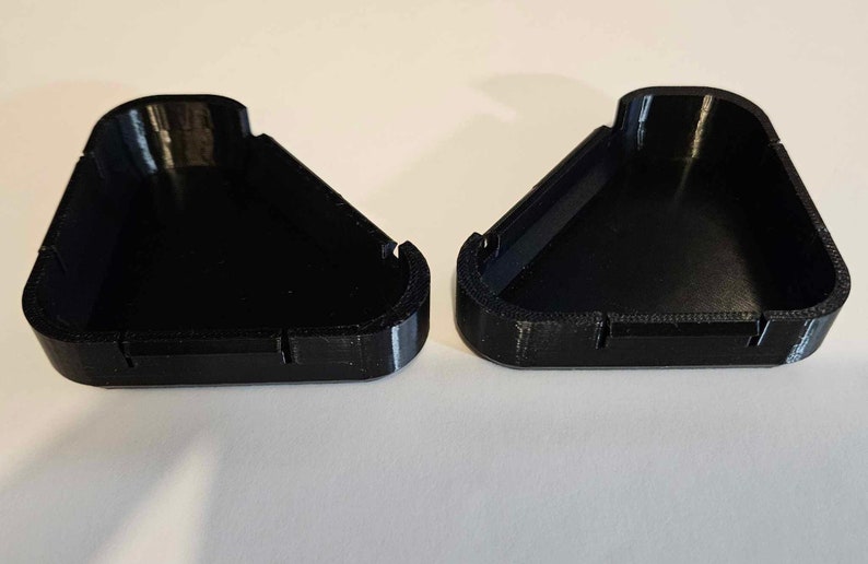 May include: Two black triangular plastic containers with a smooth, glossy finish. The containers are open and appear to be part of a set.