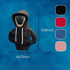 May include: A black hooded sweatshirt with white drawstrings and red stitching on the pockets. The figure is 5.18 inches tall and 4.47 inches wide. The background is a gradient of blue. There are color swatches of black, red, blue, and pink.