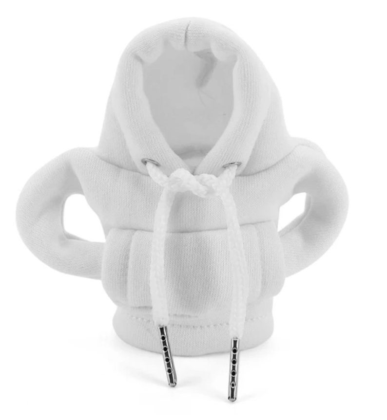 May include: A white miniature hoodie with a drawstring and silver-colored metal aglets. The hoodie has a hood and sleeves, and is made of a soft, textured fabric. The design is a novelty item.