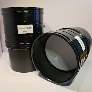 Może przedstawiać: Dwa czarne plastikowe złączki rur z etykietą sita 50 mikronów. Złączki są przeznaczone do systemów wodno-kanalizacyjnych lub drenażowych.
