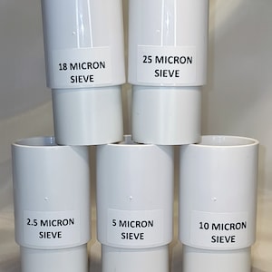 Może przedstawiać: Pięć białych plastikowych wkładów filtrujących z etykietami wskazującymi różne rozmiary mikronów: 2,5 mikrona, 5 mikronów, 10 mikronów, 18 mikronów i 25 mikronów.