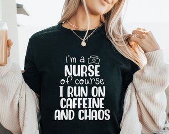May include: A black t-shirt with white text that reads "I'm a nurse of course I run on caffeine and chaos". The text includes a small nurse's cap icon.