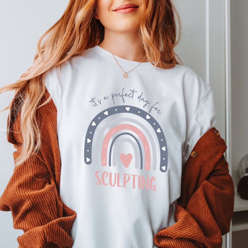May include: White t-shirt with a rainbow design and the text "it's a perfect day for SCULPTING".