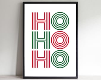 May include: A framed print with the word "HO HO HO" in red and green. The letters "H" are vertical lines, and the "O"s are concentric circles. The print is on a white background and framed in black.