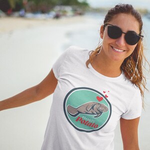 May include: White t-shirt with a green circle graphic featuring a cartoon manatee with the text "Floaty Potato" in red.