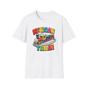 May include: A white short-sleeve t-shirt featuring a colorful graphic of a train made of dice and dominoes on a track. The text "MEXICAN TRAIN" is printed in bold, multi-colored letters above and below the train illustration on the front.