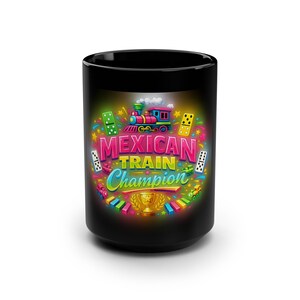 May include: Black ceramic mug featuring a colorful design with the text "MEXICAN TRAIN Champion". The design includes a train, dominoes, stars, and a trophy. The mug is cylindrical and has a glossy finish.