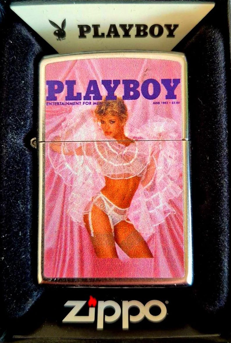 May include: A vintage Zippo lighter with a Playboy magazine cover from June 1982. The cover art depicts a woman in lingerie against a pink background. The lighter is in a black case, with the Playboy logo and Zippo branding.