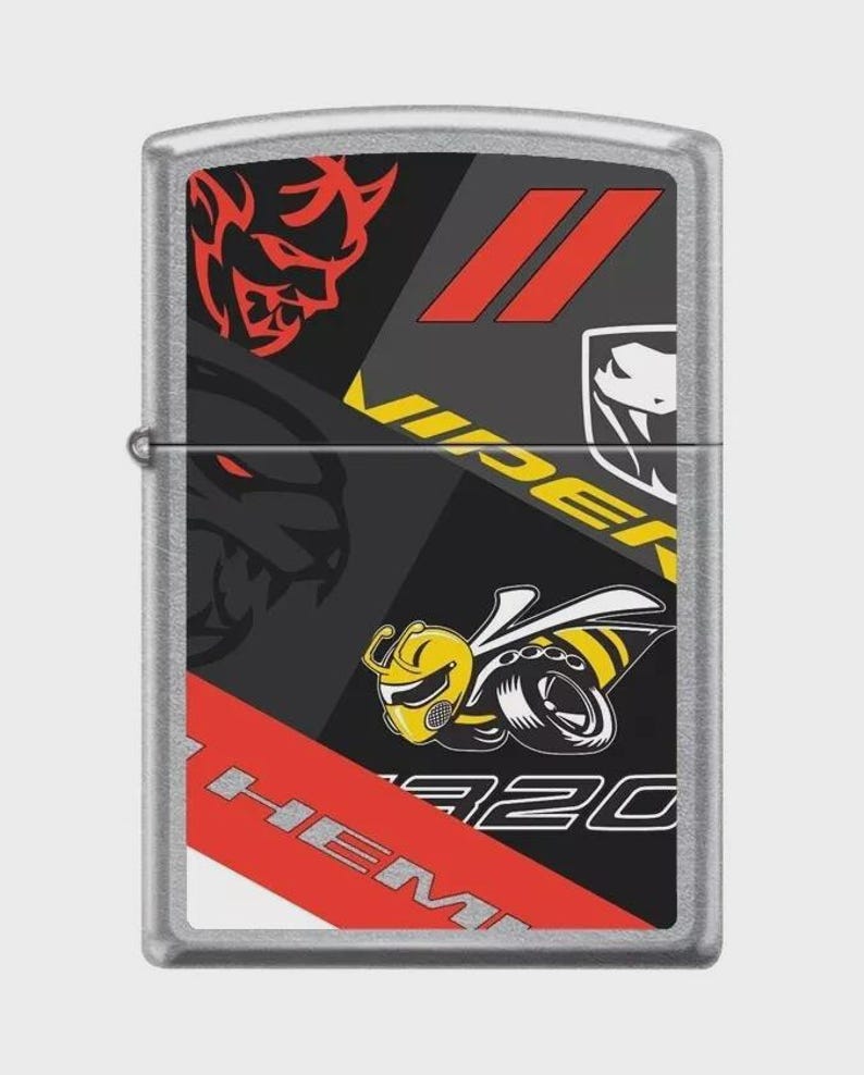 May include: Silver metal lighter with a graphic design featuring red, black, and yellow elements. The design includes the word "VIPER", a stylized bee, and the text "HEMI". The lighter has a rectangular shape.