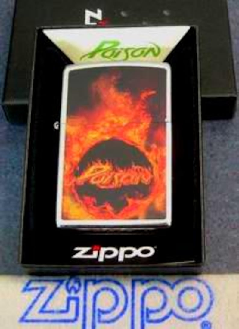 Pu&ograve; includere: Un accendino Zippo argentato con un design infuocato con la parola "Poison" in un cerchio nero, su uno sfondo di fiamme. L'accendino &egrave; esposto in una scatola nera con il logo Zippo.