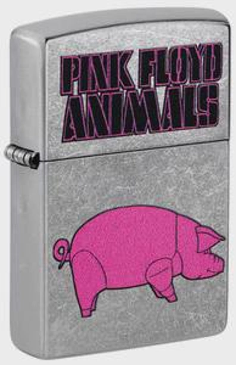 Puede incluir: Un encendedor de metal plateado con el texto "PINK FLOYD ANIMALS" en rosa y negro. Debajo, una ilustraci&oacute;n de un cerdo rosa. El encendedor tiene forma rectangular y una tapa con bisagras.