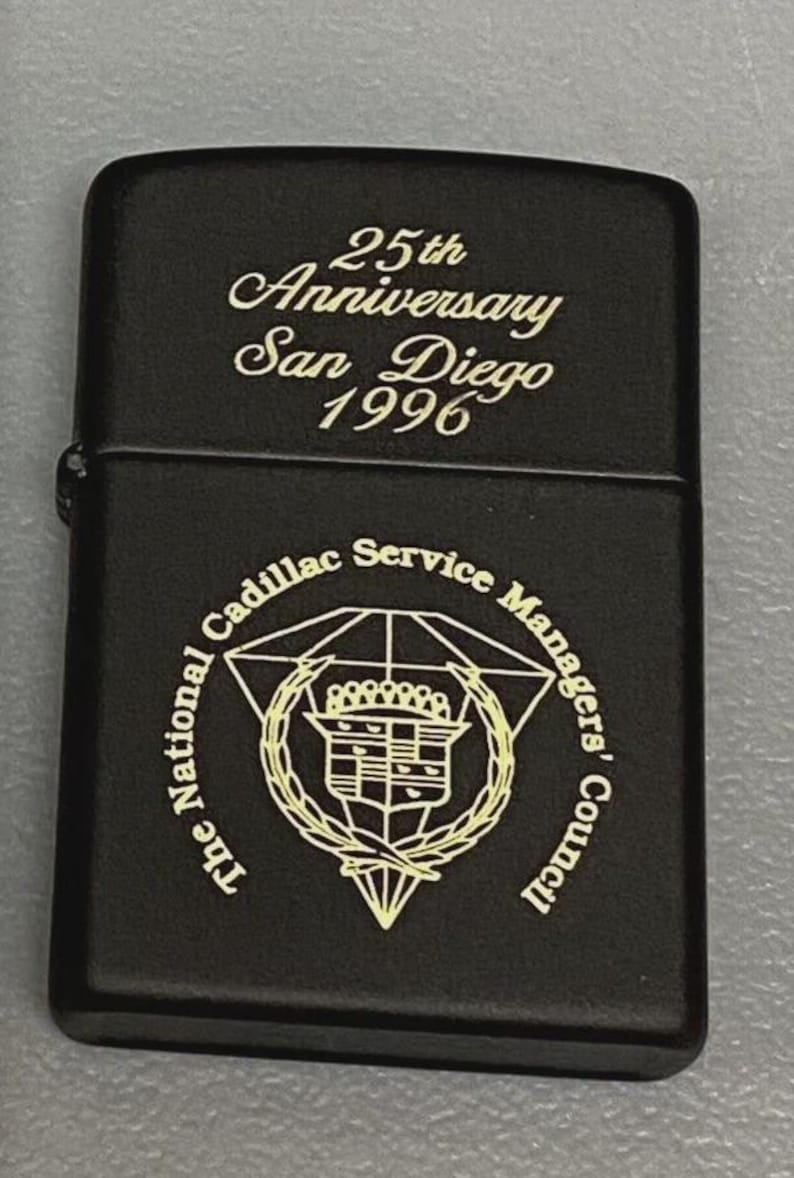 Pu&ograve; includere: Accendino in metallo nero con la scritta "25th Anniversary San Diego 1996". L'accendino presenta anche il logo del National Cadillac Service Managers' Council in oro.