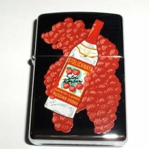 以下が含まれることがあります： 黒色の背景に、銀色のライター。赤いラズベリーと白い文字で、ストリチナヤ ラズベリーフレーバー ロシアンウォッカのボトルが描かれている。ボトルは赤いラズベリーで囲まれている。