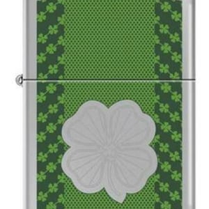 Może przedstawiać: Srebrna zapalniczka z zielonym i białym wzorem. Wzór przedstawia koniczynę czteroliścienną na zielonym tle z białą obwódką.