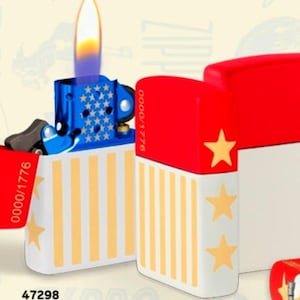 May include: A patriotic-themed lighter with a blue top decorated with white stars and a red lid featuring a gold star. The body is white with yellow stripes and gold stars. The lighter is lit, showing a flame.