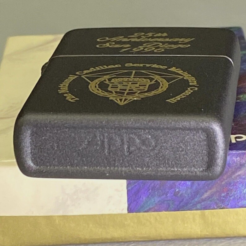 Pu&ograve; includere: Un accendino in metallo nero con scritte dorate. La parte superiore dell'accendino riporta la scritta "25th Anniversary San Diego 1996". L'accendino presenta anche la scritta "The National Cadillac Service Managers Council".