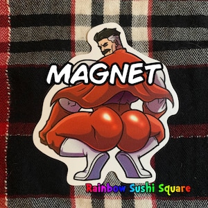May include: A sticker with the word "MAGNET" in bold white letters. The sticker features a cartoon illustration of a muscular character in a red cape and white pants. The text "Rainbow Sushi Square" is at the bottom.