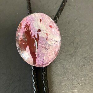 Bolo tie with a glass hand painted design, with tips in silver or brass and a leather cord.