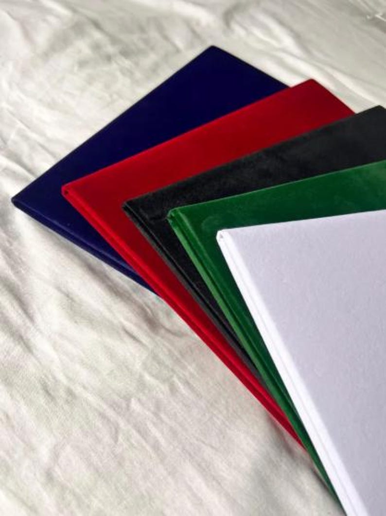 Op de afbeelding: Een stapel kleurrijke, rechthoekige stofstalen. De kleuren zijn marineblauw, rood, zwart, groen en wit. De stalen zijn in lagen gerangschikt, waarbij de randen van elke kleur zichtbaar zijn.