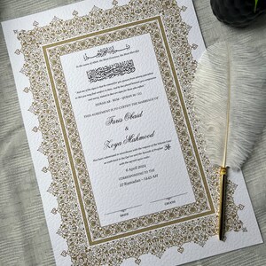 Op de afbeelding: Een formeel huwelijkscertificaat met sierlijke gouden filigraanranden en tekst in het Arabisch en Engels. Het document certificeert het huwelijk van Faris Obaid en Loya Mahmood, gedateerd 6 april 2024. Een witte veer ligt ernaast.