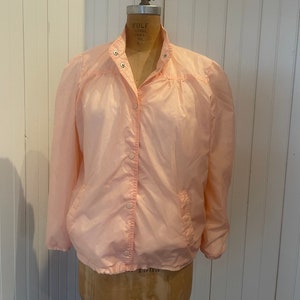 May include: A light pink nylon jacket with a snap closure and a drawstring waist.