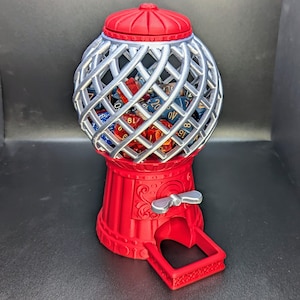 May include: A red and silver gumball machine style dice tower with a silver wire cage and a crank on the side. The cage is filled with colorful polyhedral dice.