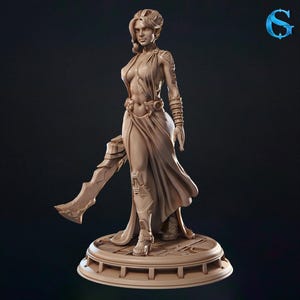 Puede incluir: Figura detallada de una mujer con un vestido fluido, sosteniendo una gran espada. La figura está en una pose dinámica, con detalles intrincados en la ropa y la base. El color es marrón claro, con un fondo oscuro.