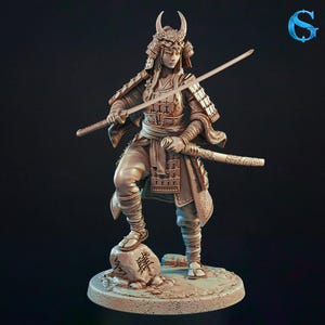May include: A detailed figurine of a samurai warrior in full armor, holding two katanas. The figure is posed on a stone base with Japanese characters. The armor and helmet feature intricate designs, and the overall color is a muted bronze.