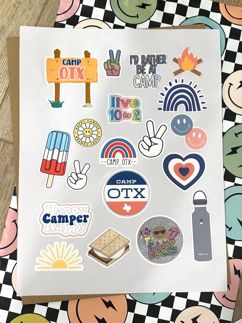 May include: A sheet of stickers with a camp theme. The stickers feature a variety of designs, including a sign that says "Camp OTX", a peace sign, a campfire, a rainbow, a popsicle, a heart, a s'more, a sun, and a water bottle. The stickers are perfect for adding a touch of summer fun to your belongings.