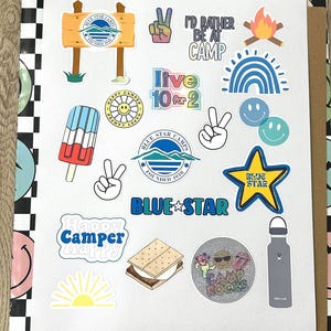 May include: A collection of colorful stickers featuring camping-themed designs, including a peace sign, a campfire, a rainbow, a smiley face, a popsicle, a s'more, a water bottle, and a sun. The stickers also feature text that says "Blue Star Camps", "Happy Camper", "Live 10 for 2", and "I'd Rather Be at Camp".