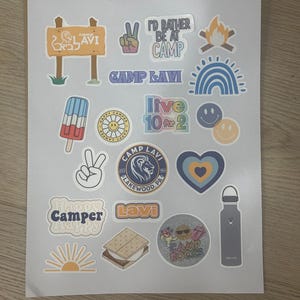 May include: A collection of colorful stickers featuring camp-themed designs, including a peace sign, a campfire, a rainbow, a popsicle, a smiley face, a heart, a sun, a s'more, a water bottle, and a lion logo with the text "Camp Lavi Lakewood, PA".