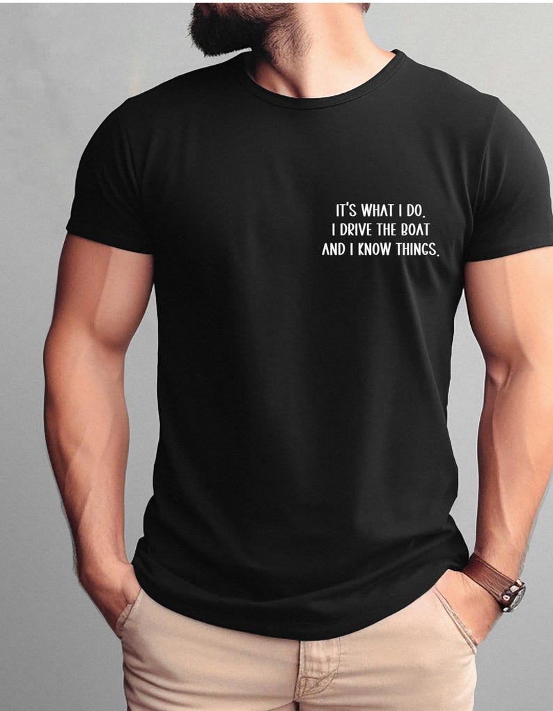 May include: Black t-shirt with white text that reads "It's what I do. I drive the boat and I know things."