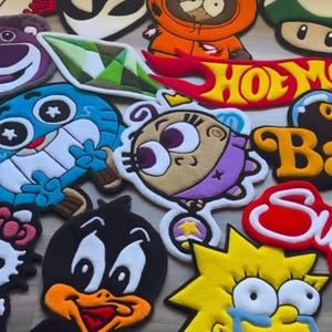 Puede incluir: Una colección de alfombras coloridas con forma de personajes de dibujos animados. Las alfombras presentan personajes como Kenny de South Park, Lisa Simpson y el Pato Lucas. Otros diseños incluyen un extraterrestre, una seta y un monstruo azul.