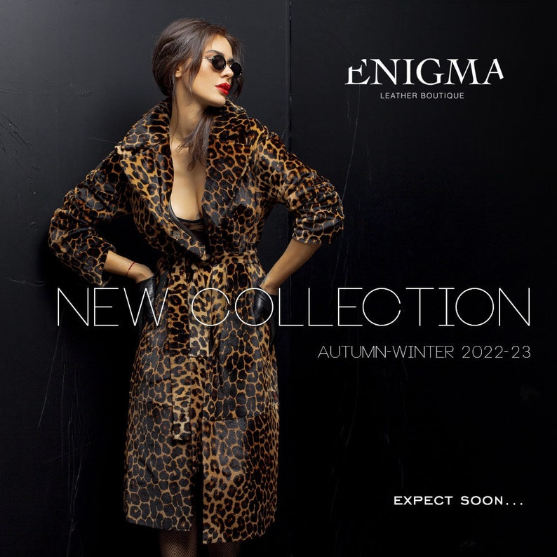 May include: A woman wearing a leopard print coat with a black belt. The text "ENIGMA LEATHER BOUTIQUE" and "NEW COLLECTION AUTUMN-WINTER 2022-23 EXPECT SOON..." is visible on the image.