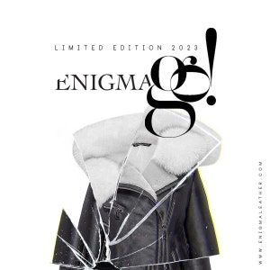 May include: A black leather jacket with a white fur collar. The jacket is broken through a pane of glass. The text "LIMITED EDITION 2023 ENIGMA" is visible above the jacket. The text "www.enigmaleather.com" is visible on the right side of the image.