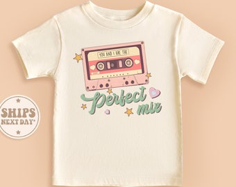 May include: A white t-shirt with a pink and green cassette tape graphic and the text "You and I are the perfect mix".