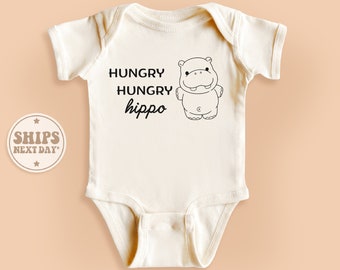 May include: White baby onesie with black text that reads "Hungry Hungry hippo" and a black and white cartoon hippopotamus illustration.