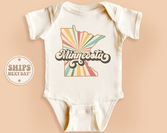 May include: White baby onesie with a retro-style graphic of the state of Minnesota with a sunburst design and the word "Minnesota" in a colorful, retro font.