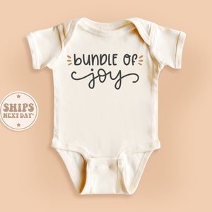 May include: White baby onesie with black text that reads "bundle of joy".
