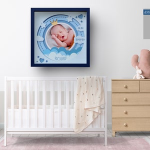 May include: A framed baby photo in a nursery setting. The blue-framed artwork features a sleeping baby with a crown, clouds, and the name "Richard." The text "ALPHABET.SVG FONT FILE INCLUDED" is visible. A white crib, dresser, and decorative items are also in the room.
