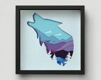 Op de afbeelding: Een kunstwerk van papier snijwerk in een zwart frame. Het silhouet van een wolf die huilt naar de maan is uitgesneden, waardoor een landschap met bergen, bomen en een meer zichtbaar wordt. De kleuren zijn blauw, paars en groen.